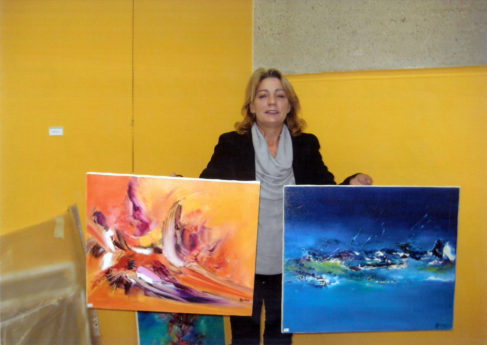 Régine Gardan présentant deux de ses tableaux abstraits lors d'une exposition